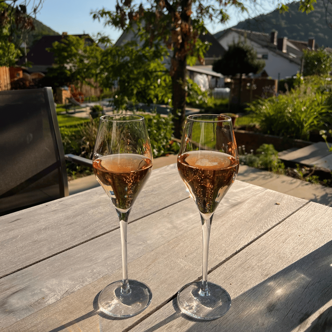 2 Gläser Rosé Sekt, im Hintergrund ein Garten