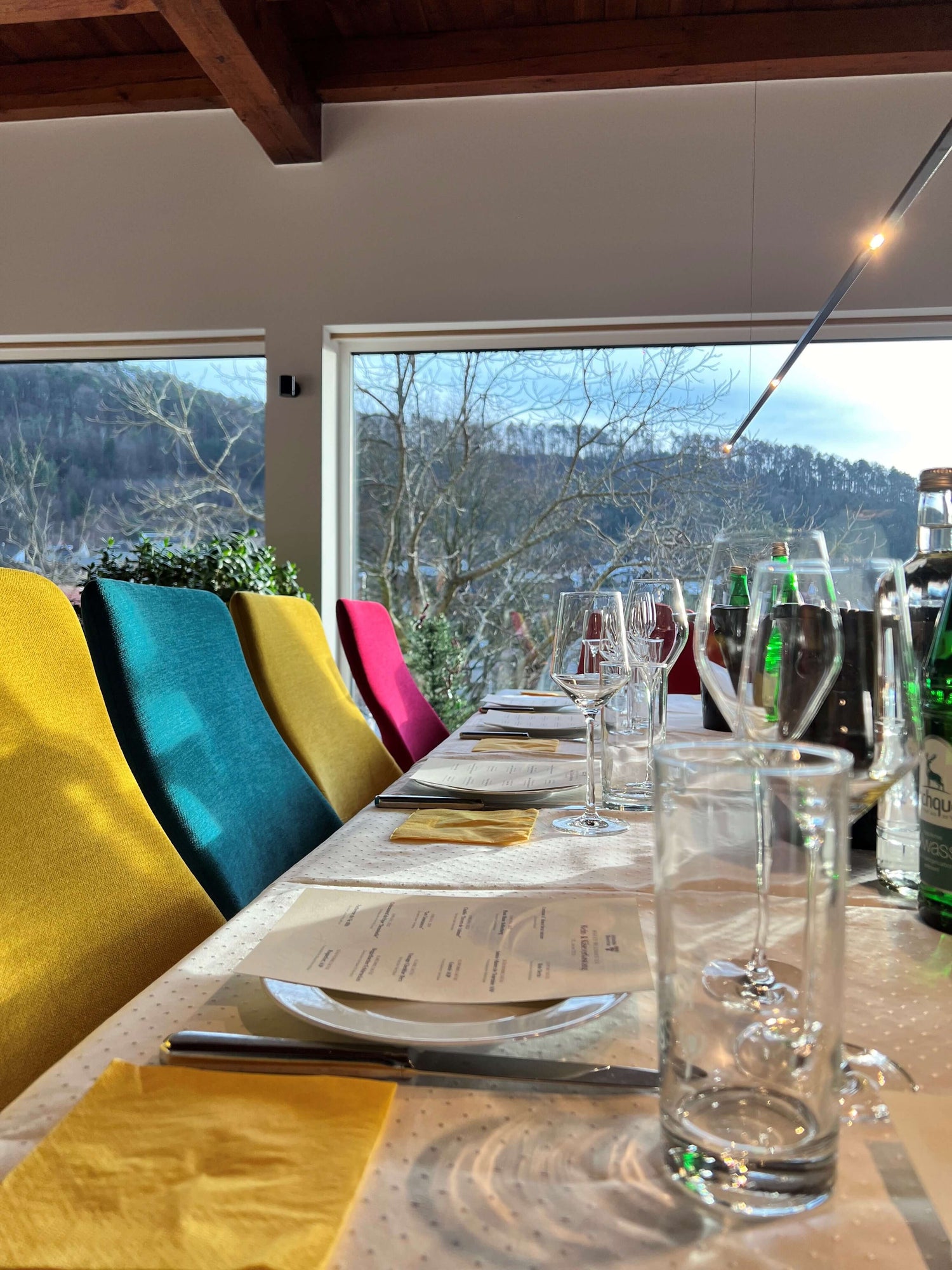 Gedeckter Tisch mit bunten Stühlen mit einem Wald im Hintergrund
